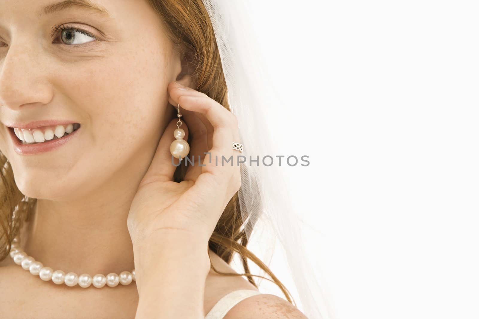 Caucasian bride adjusting her earring.