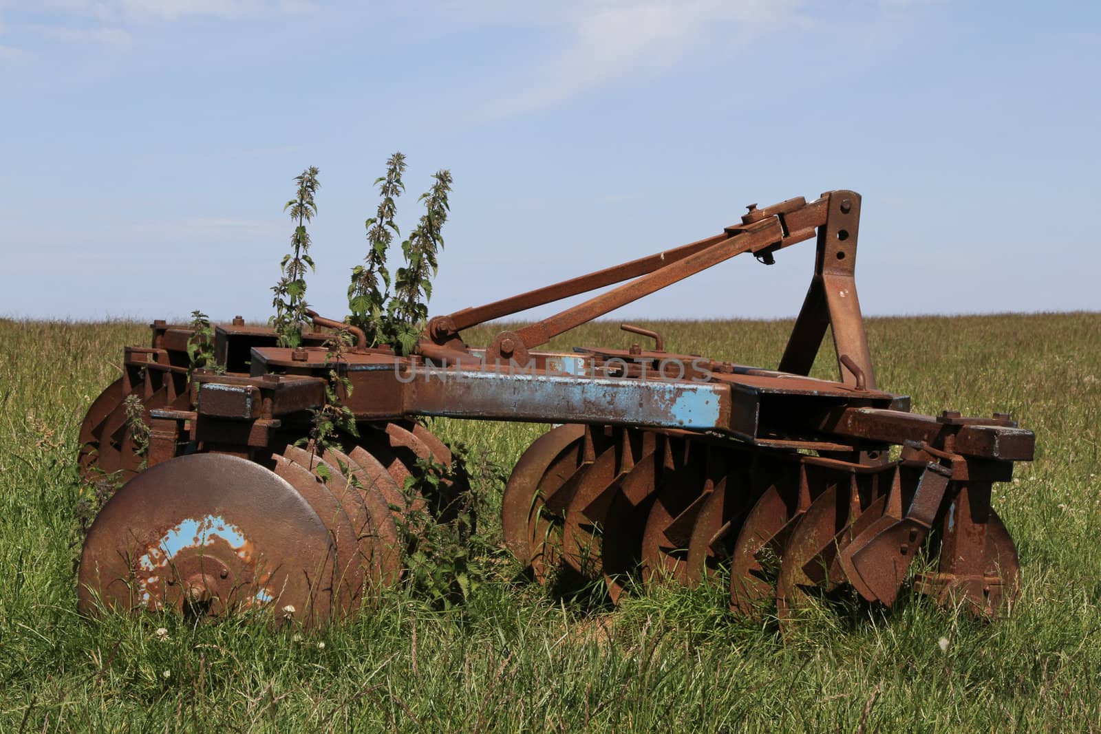 Old, rusty farm machinery in a field.