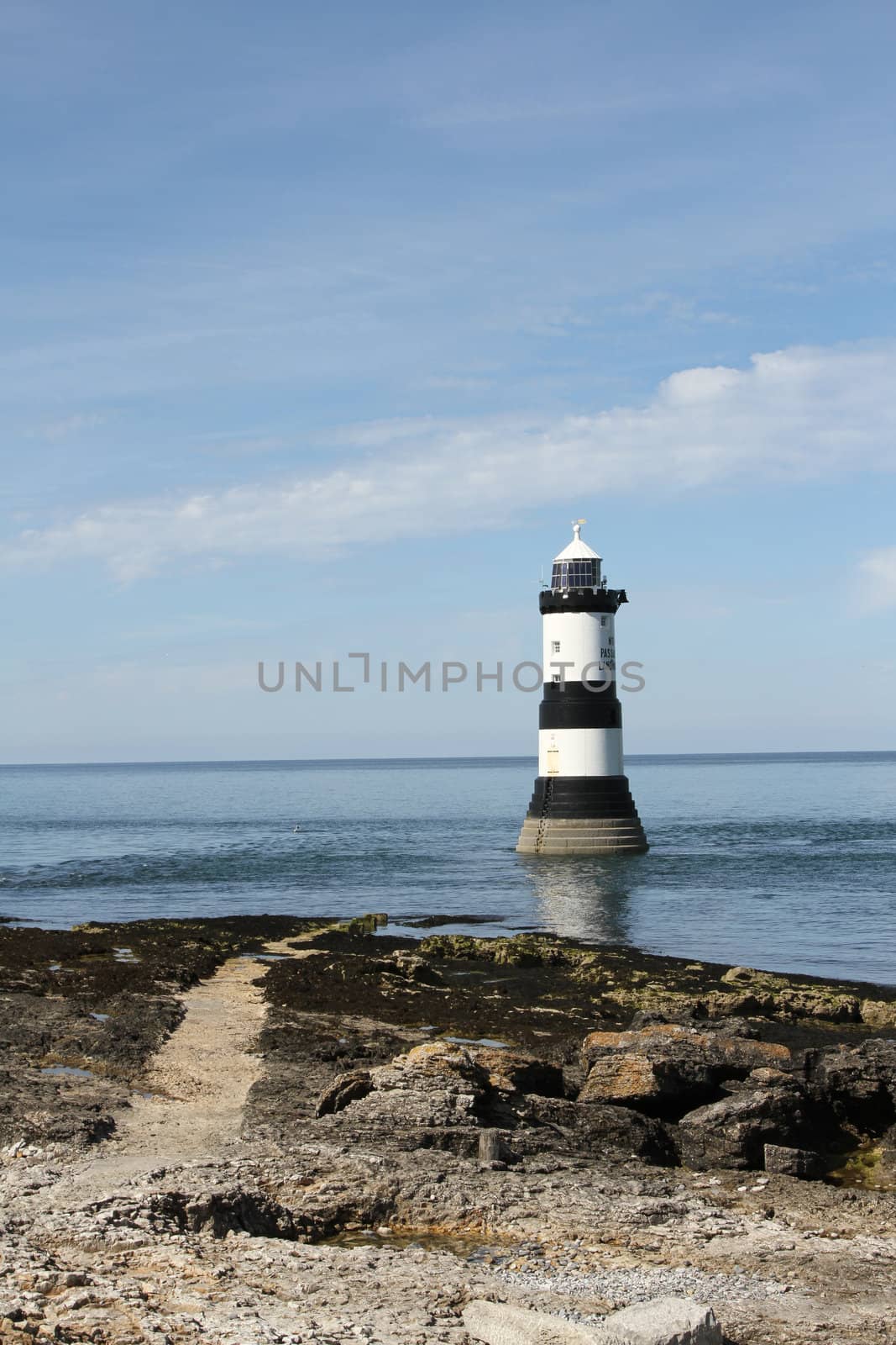 Path leading to a lighthouse in the sea.