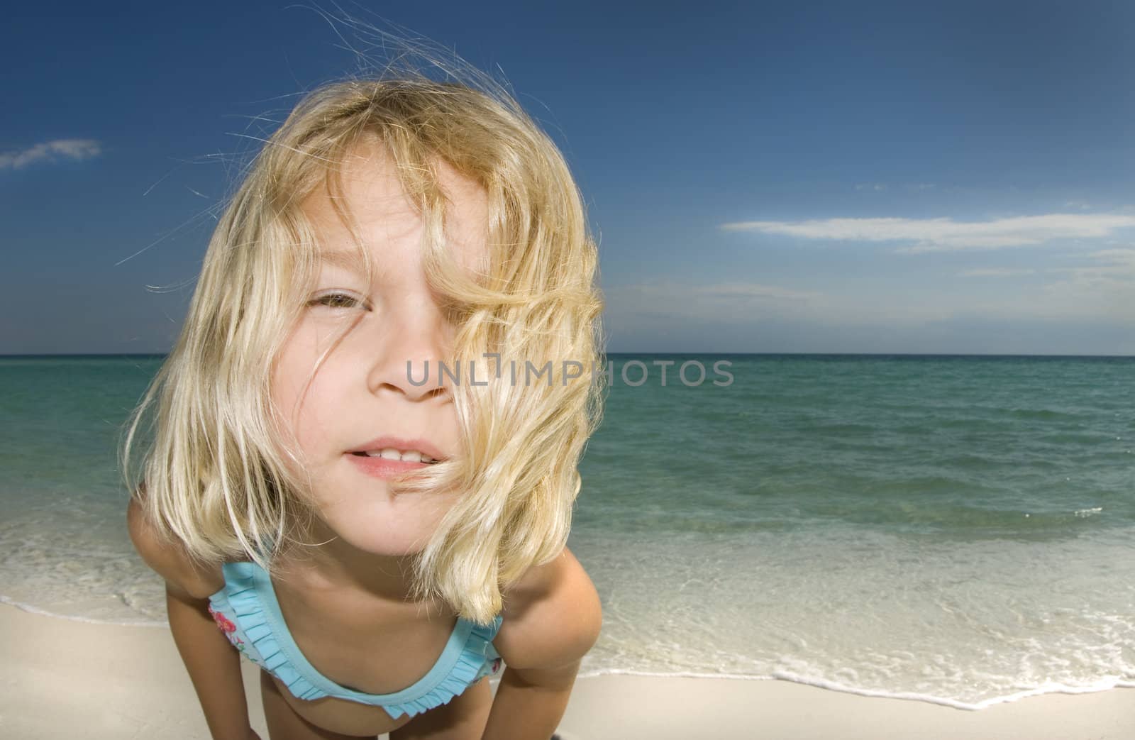 Child looking into the camera on a beautiful sunny day at the beach