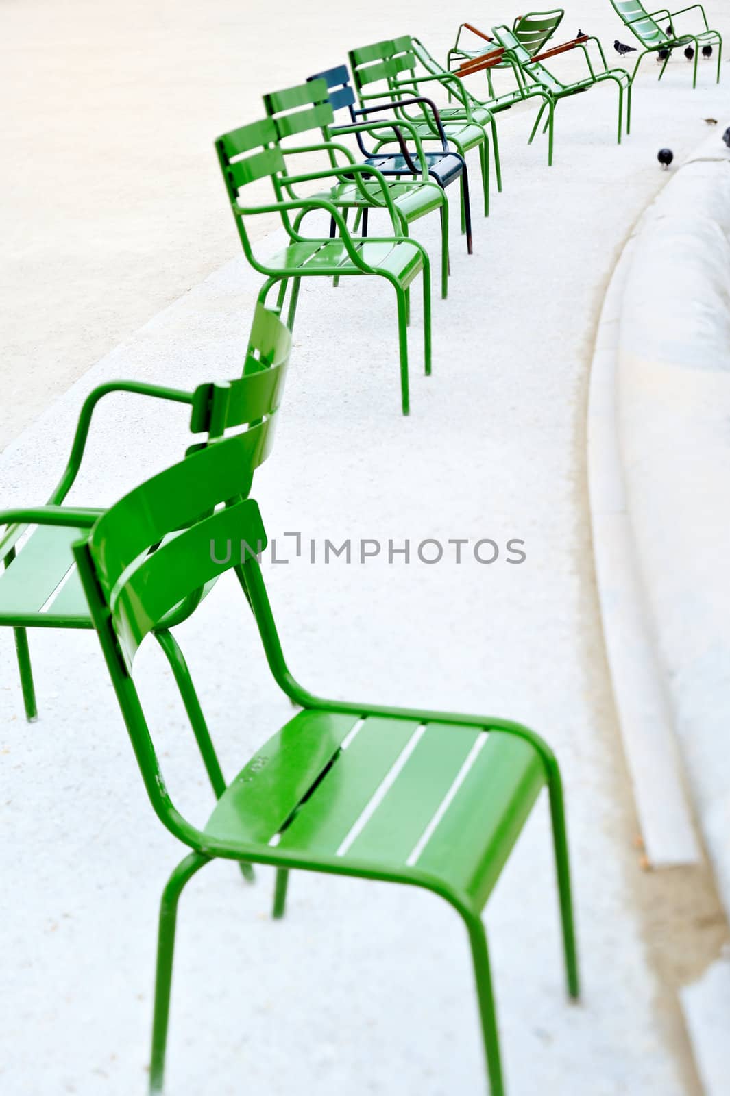 Green chairs near the fountain in the park