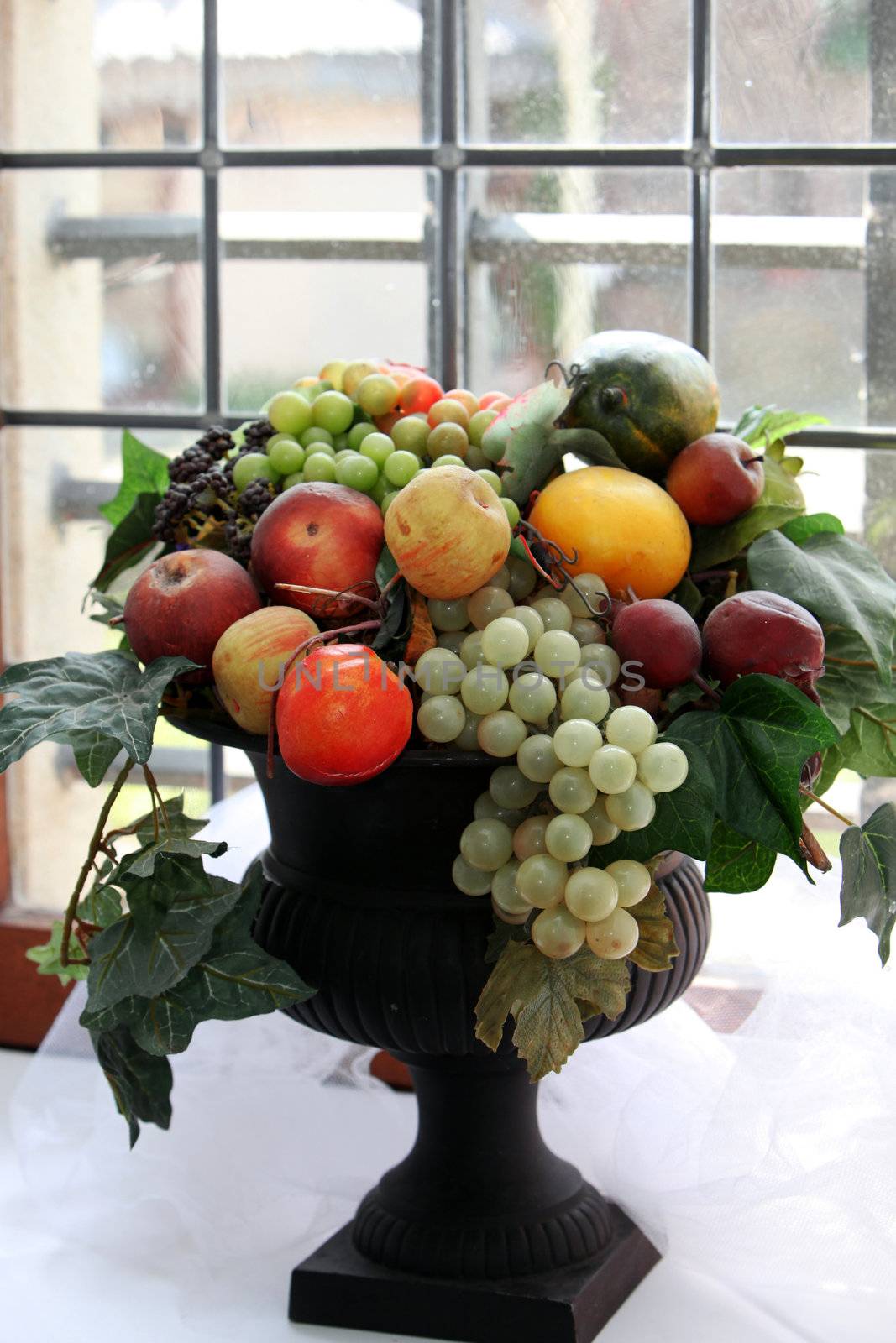 A fruit bowl with grapes and apples in an old bay window