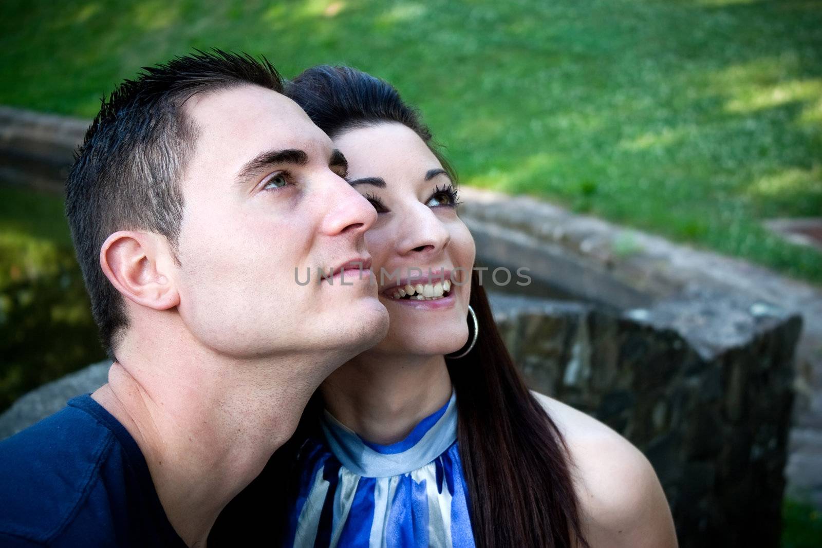 A happy young couple in their mid 20s smiling with their heads close together.