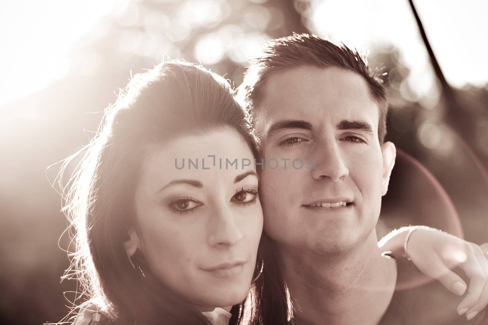 A good looking young couple posing together.  Backlit lighting with strong lens flare and sepia tone. 