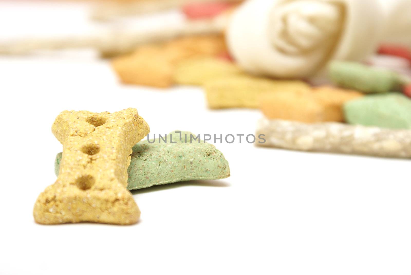 Different coloured dog treats infront of a pile of others.
