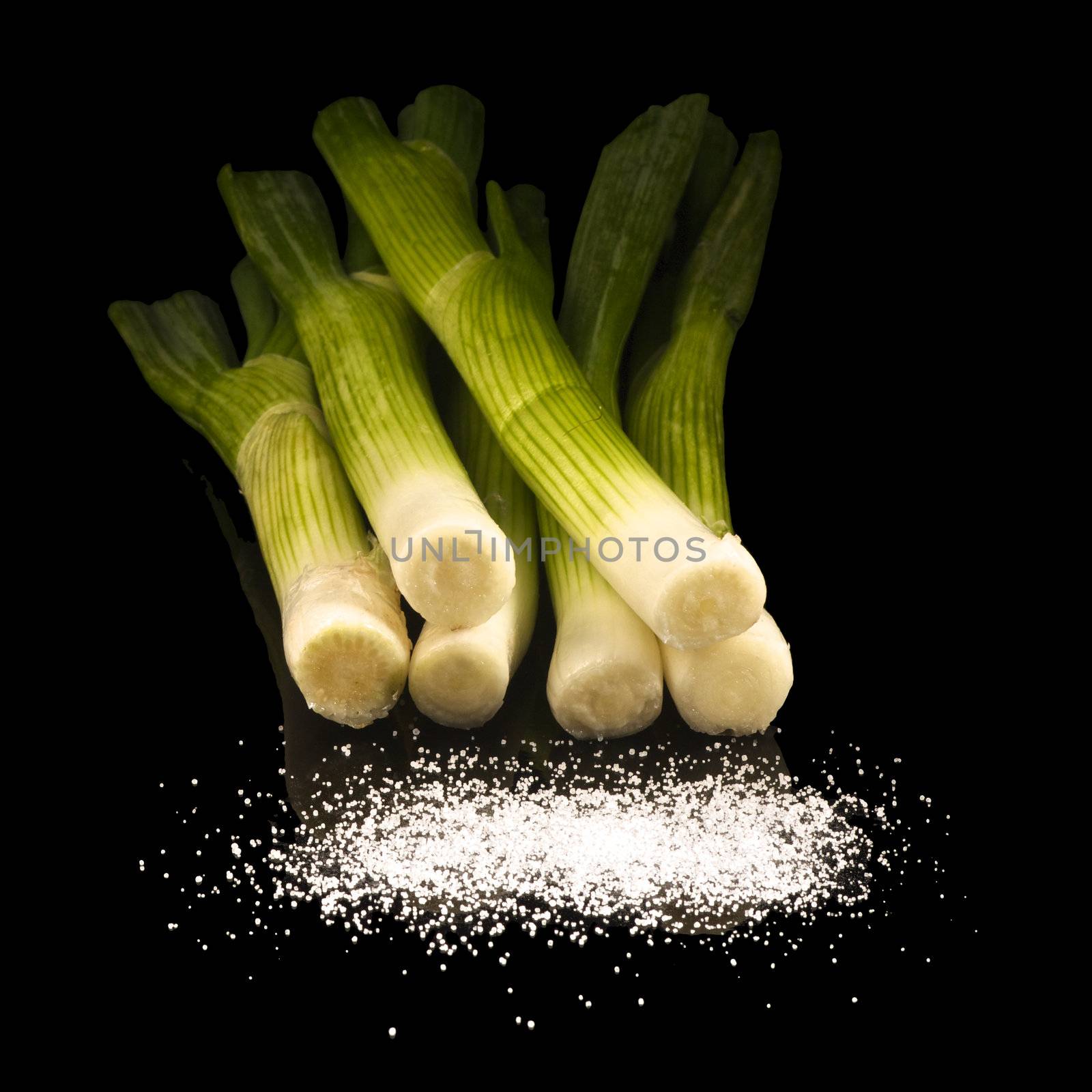 Green onions with salt isolated on black