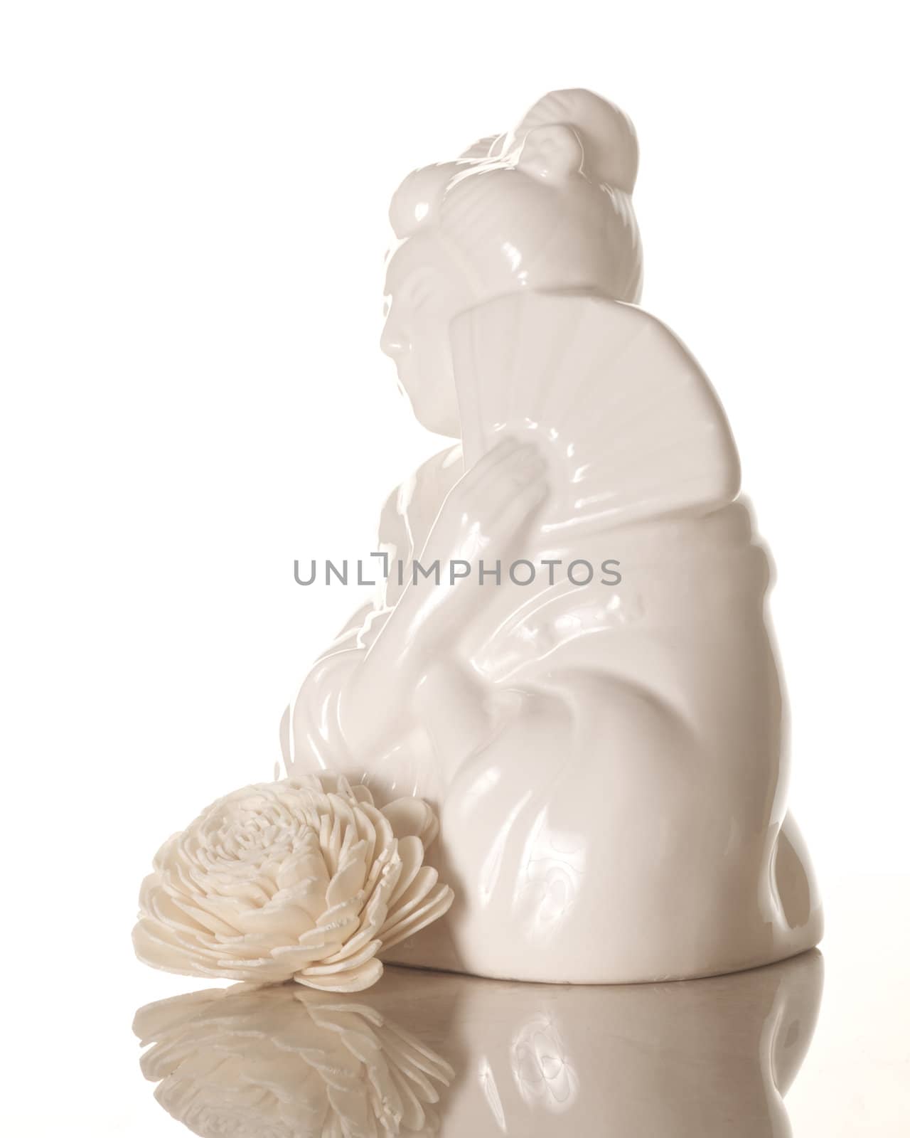 A ceramic geisha girl with white wooden flower isolated on white with reflection