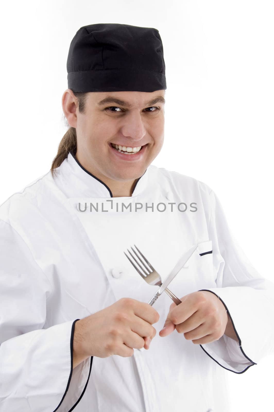 smiling young male chef holding fork and knife on an isolated white background