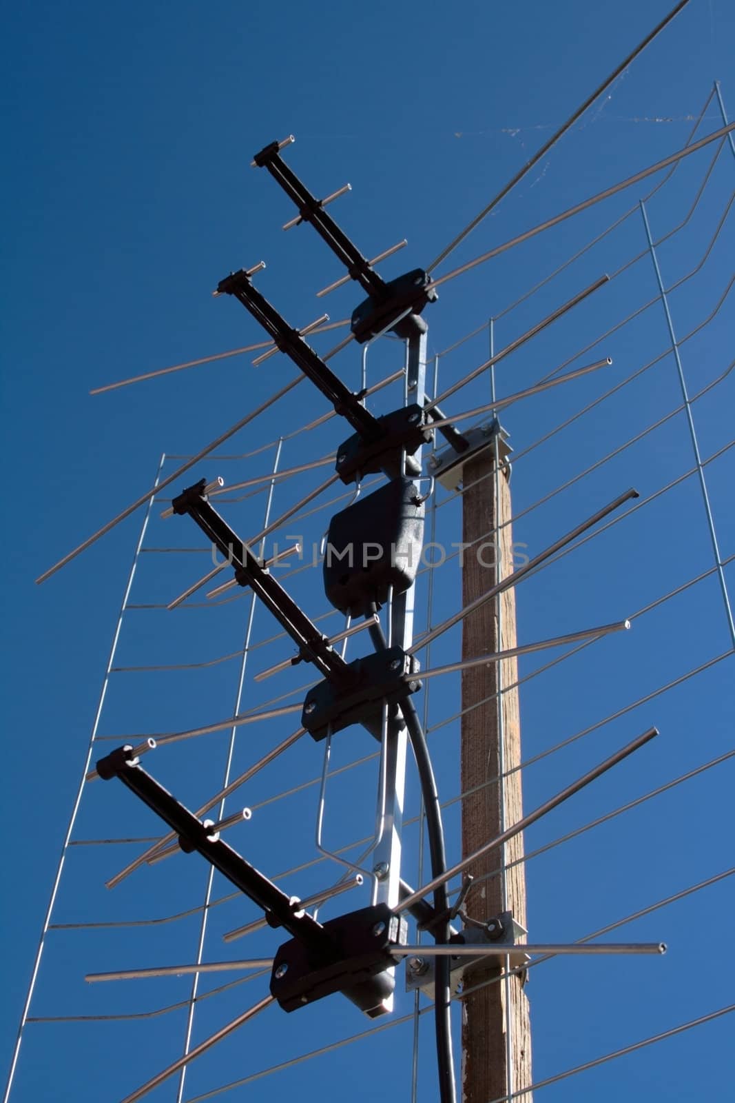 aerial TV antenna on rooftop over blue cloudless sky