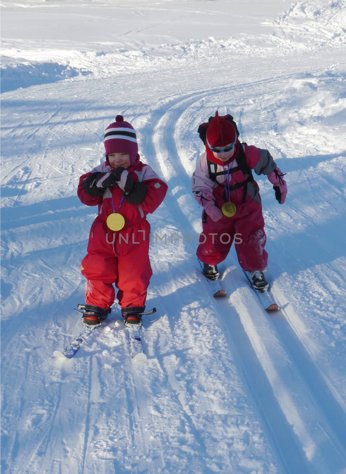 Children participating in a cross country ski race, both have won big chocolate medals