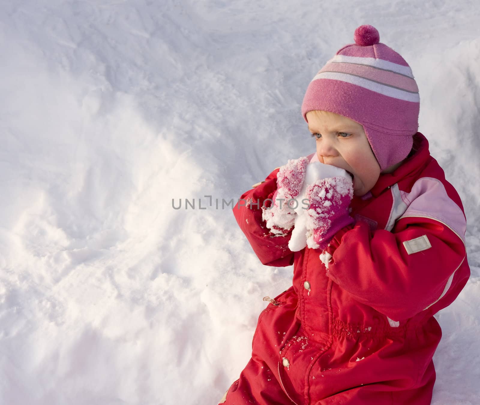 Cute little toddler (2 years old) eating snow.