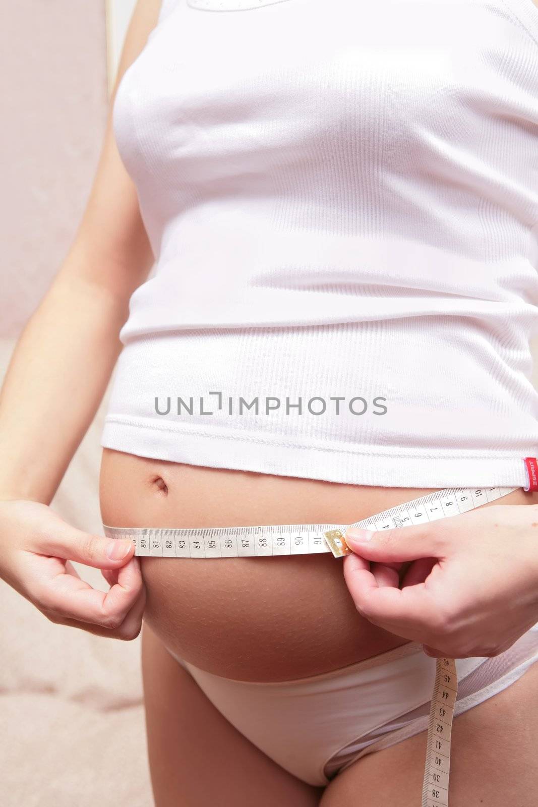 Expectant mother in white underwear measures tummy