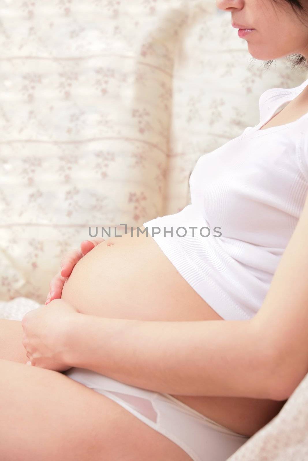Expectant mother in white underwear is stroking belly. With copy-space