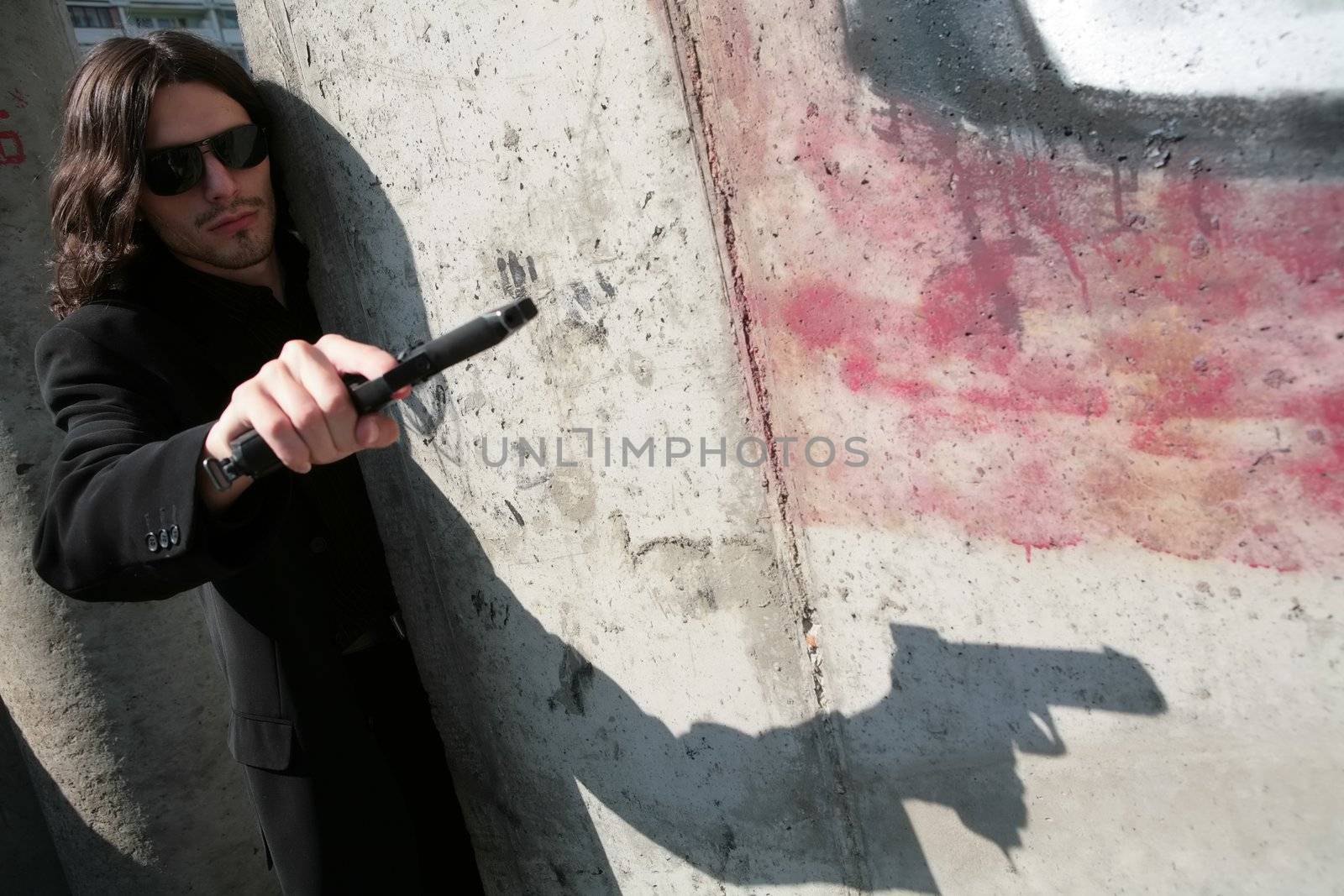 portrait man in black sunglasses and with gun in image of the gangster