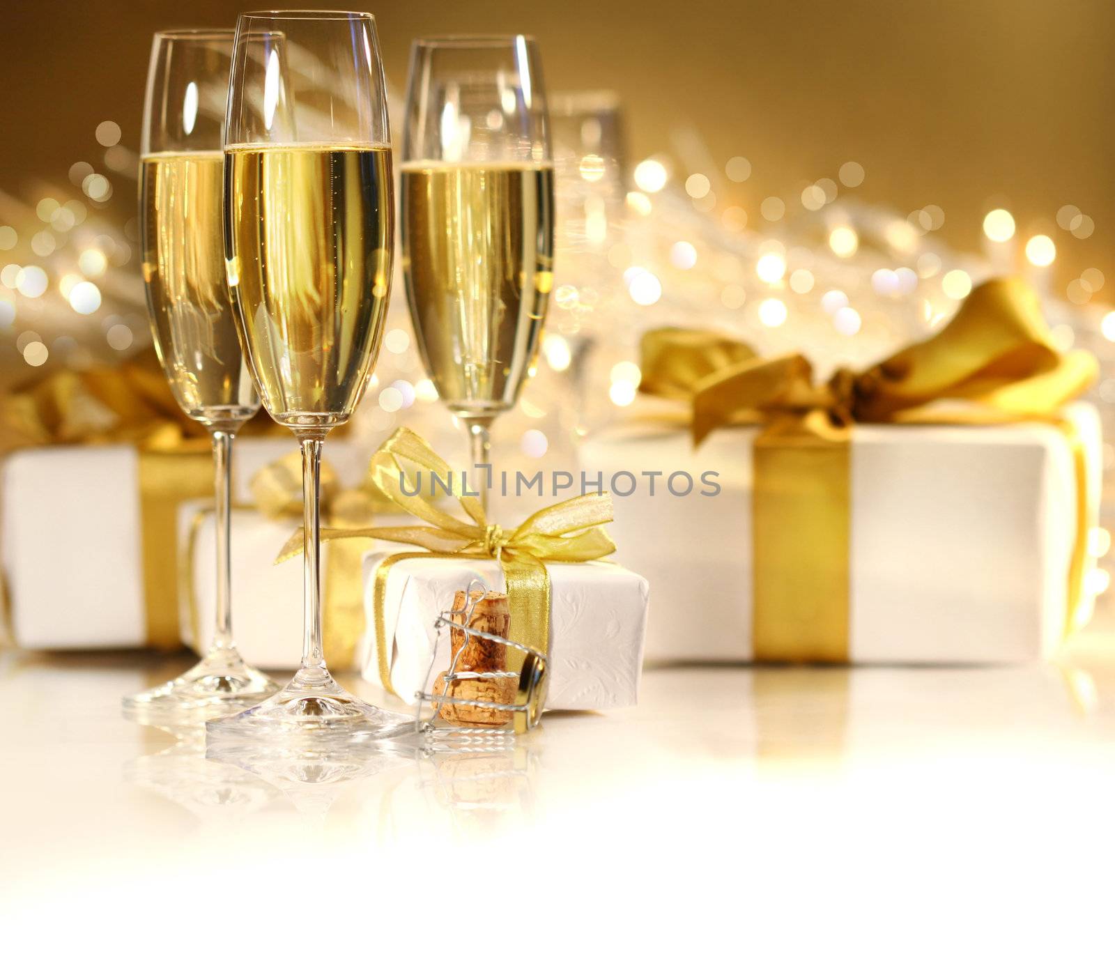 Glasses of champagne with gold ribboned gifts 