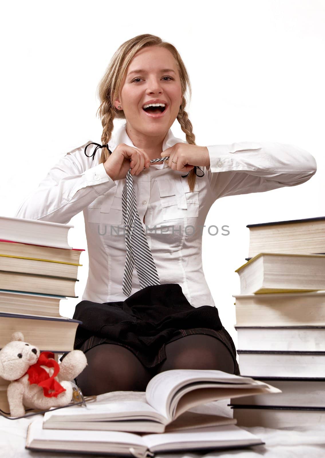 Schoolgirl or student taking off tie. She is fed up with a learning. Is time for the game. Isolated on white. 