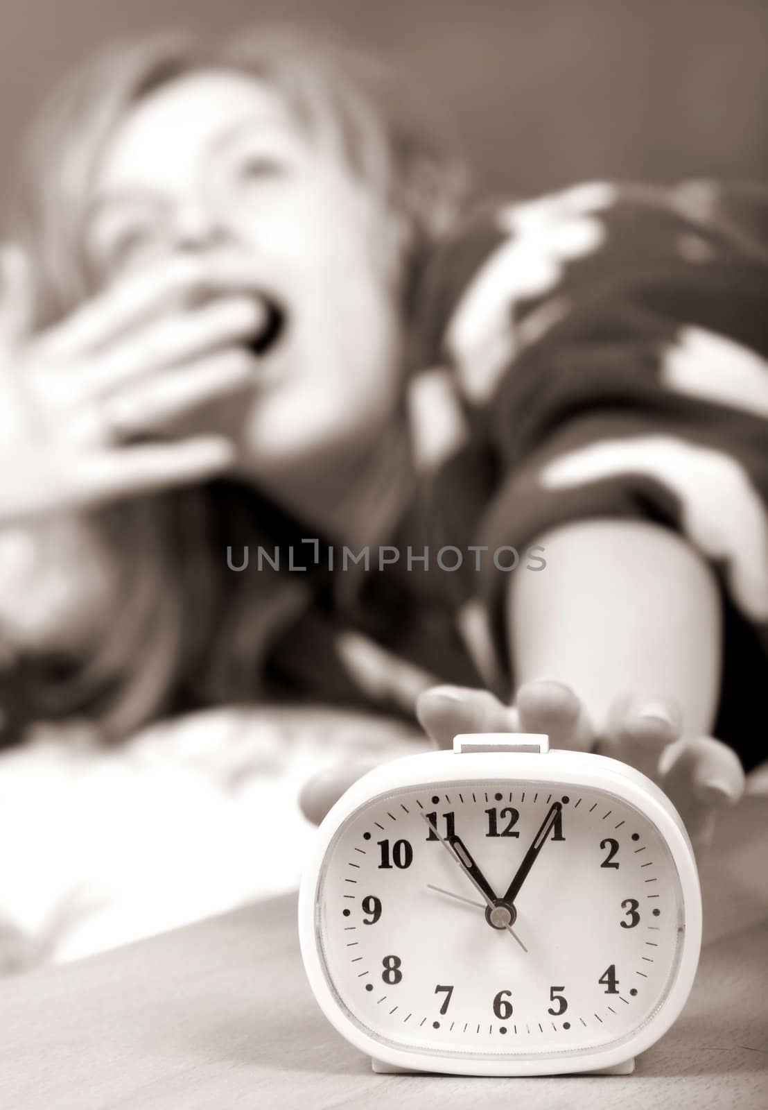 sleepy woman shuts off  alarm clock