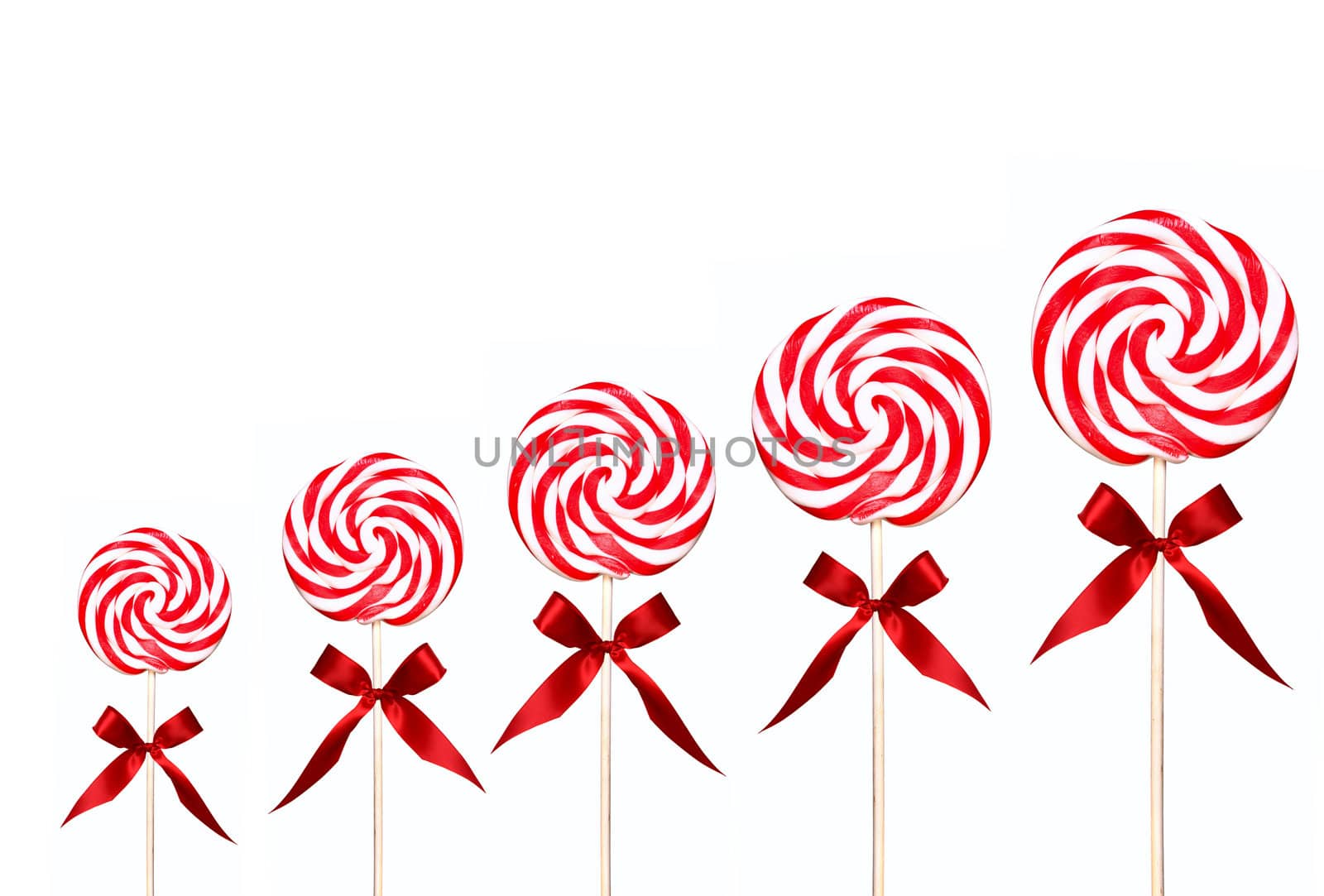 Holiday Candy Swirl Lollipops In A Line on White Background With Red Bow