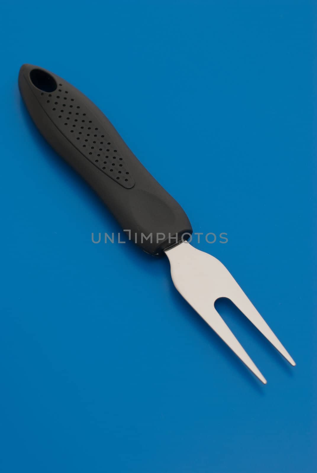 Small barbecue carving fork isolated on the blue background.