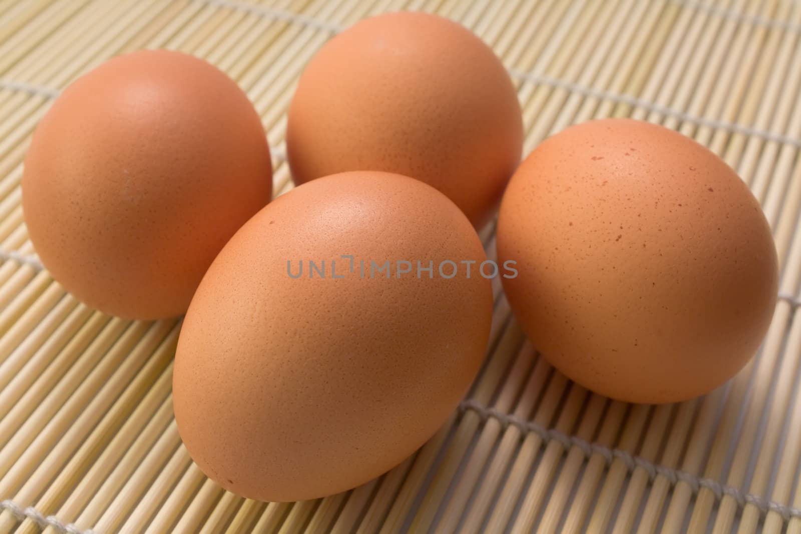 4 Brown eggs on a straw rug