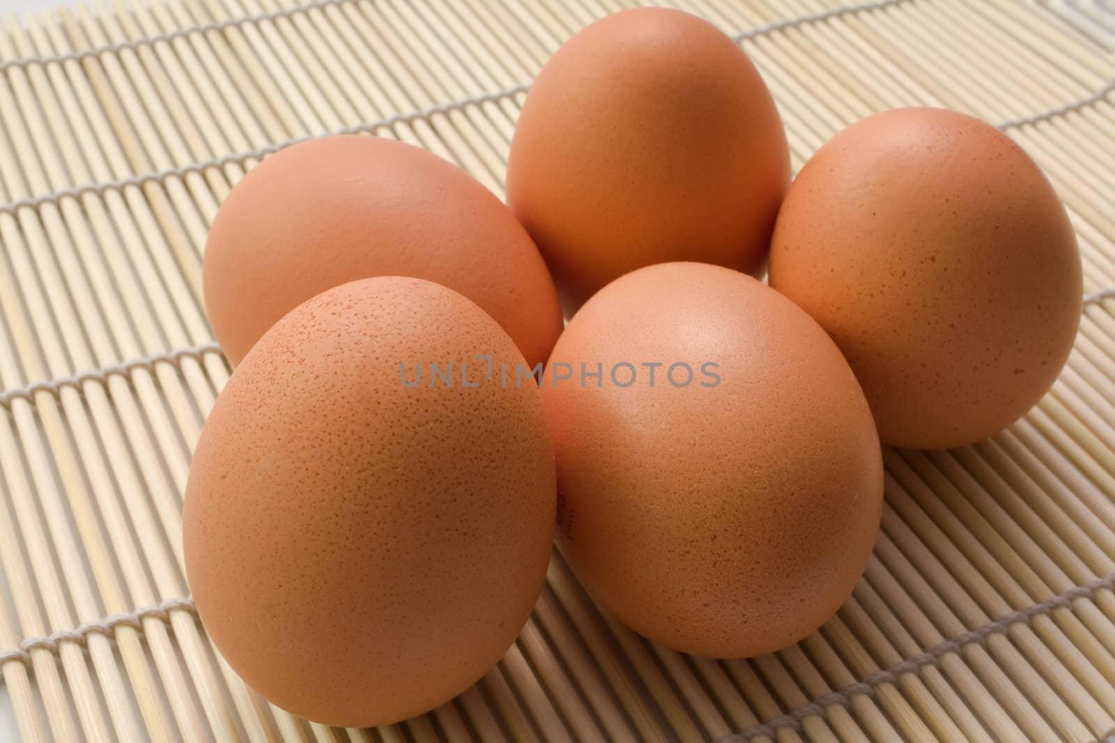 5 Brown eggs on a straw rug