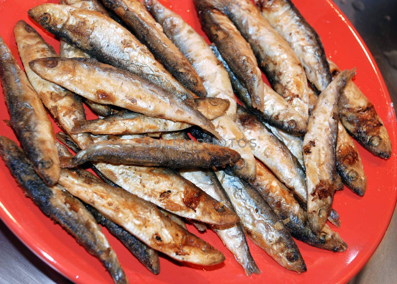 heap of small fried fish on red plate
