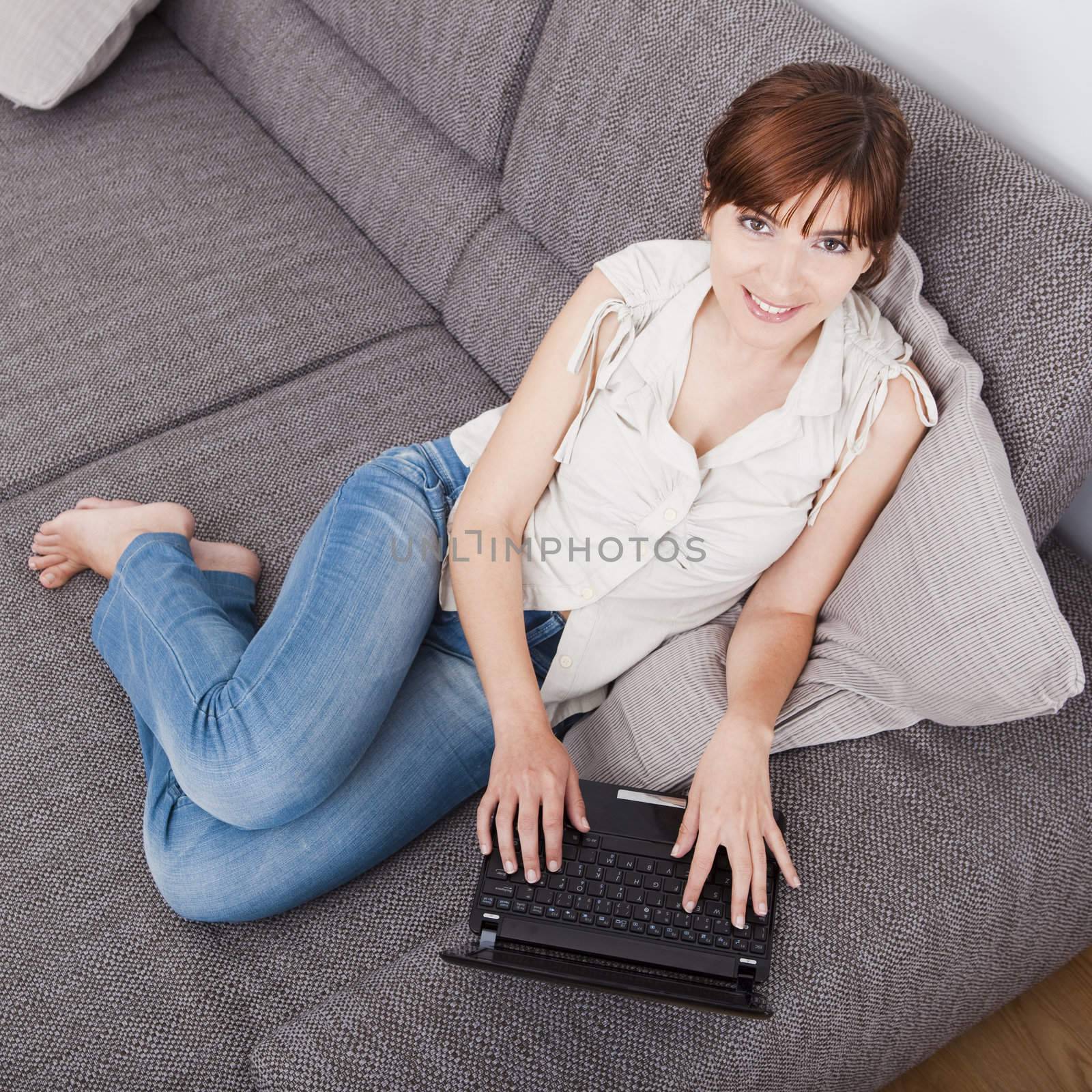 Beautiful woman at seated on sofa and working with a laptop