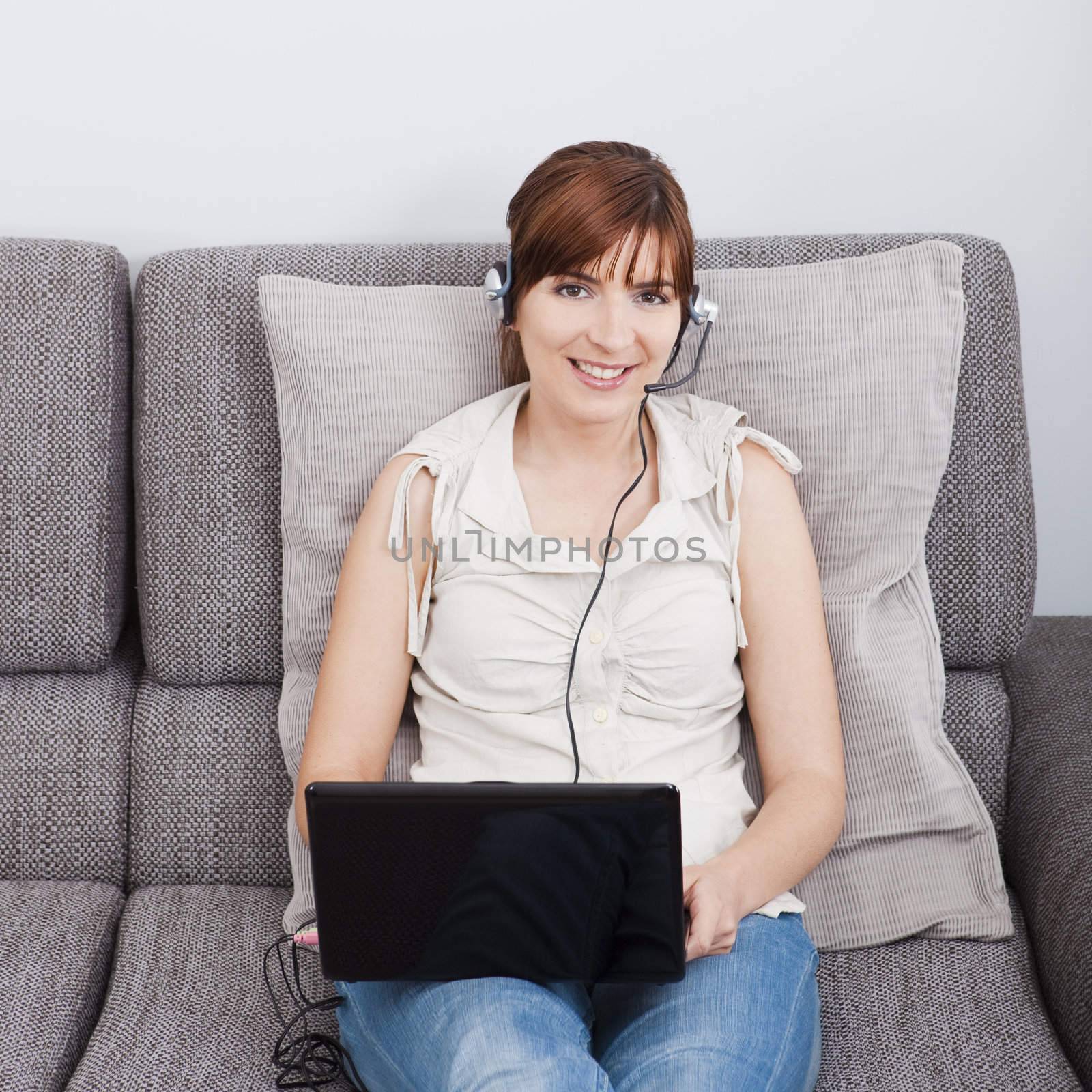 Beautiful woman at home seated on sofa, and speaking online over the internet