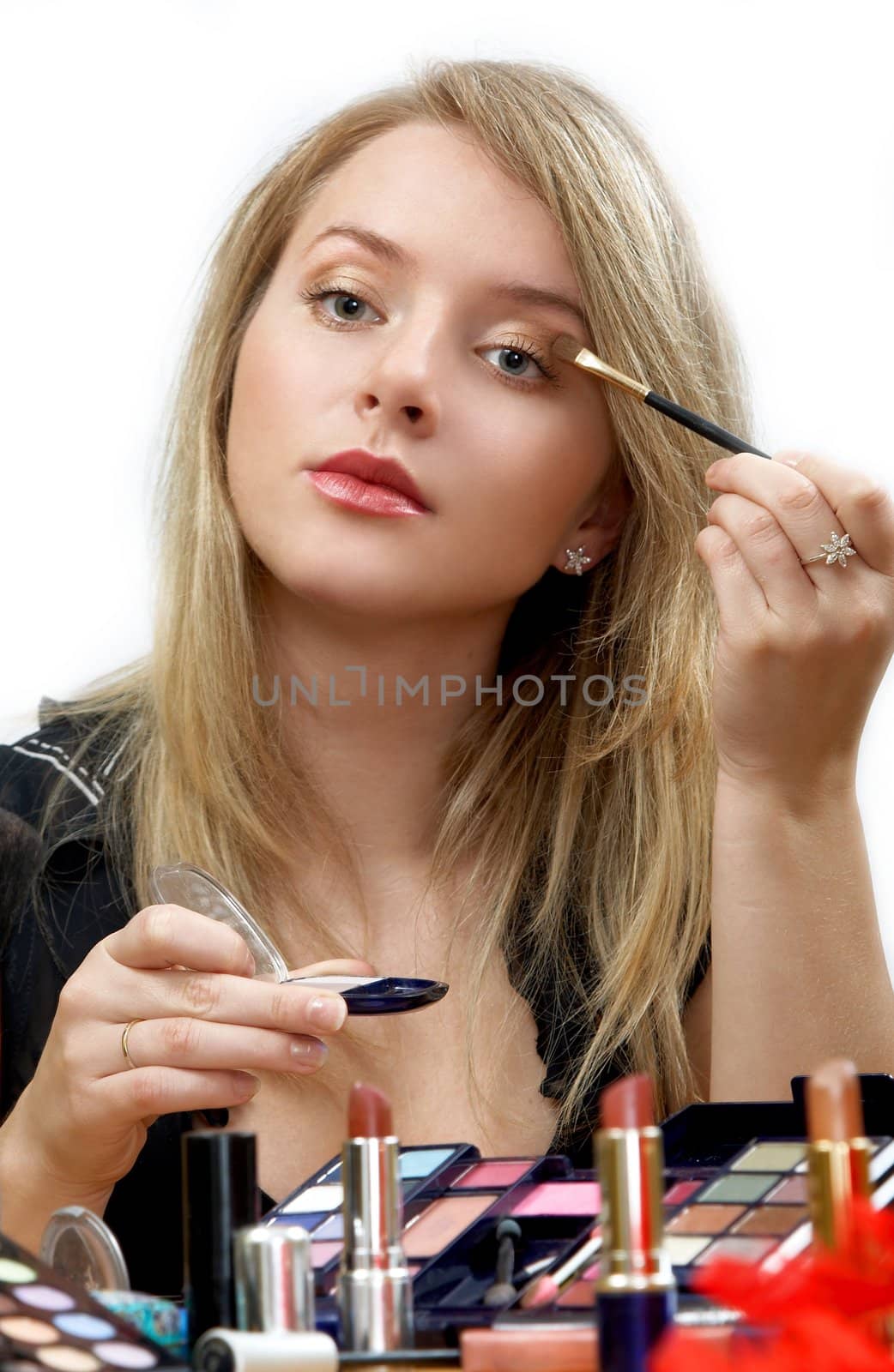 young beautiful woman is making up for itself in front of a mirror