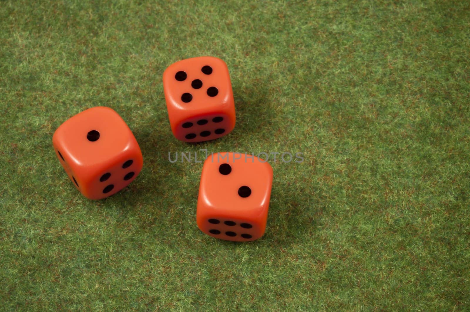 Three orange dice over a red and green carpet