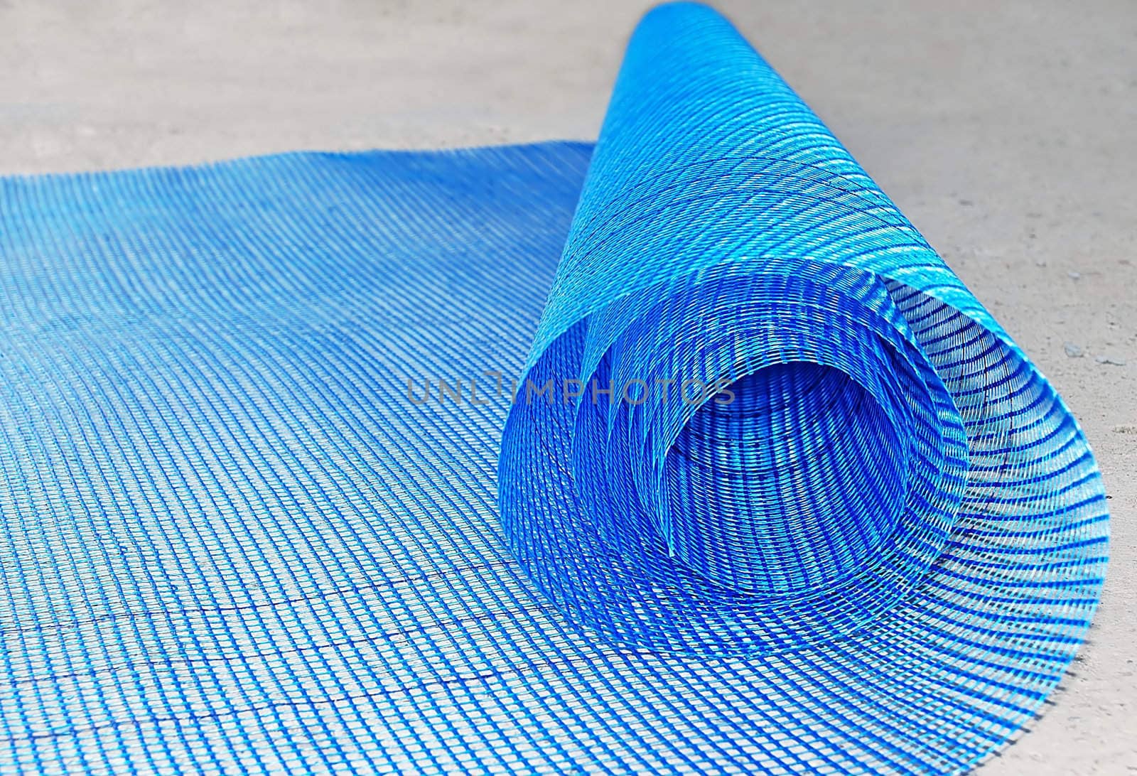 Blue plastic net roll rolled out over concrete