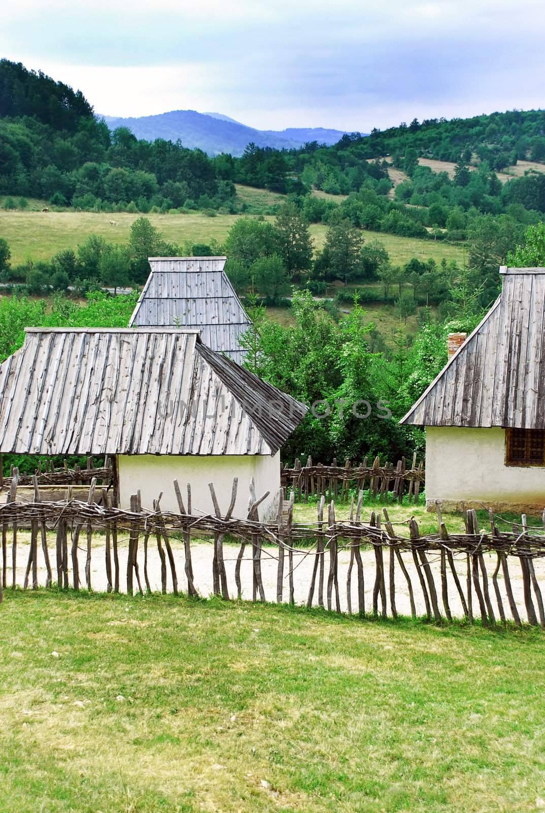 Ethnic Serbia, wooden house behind fence over rural landscape