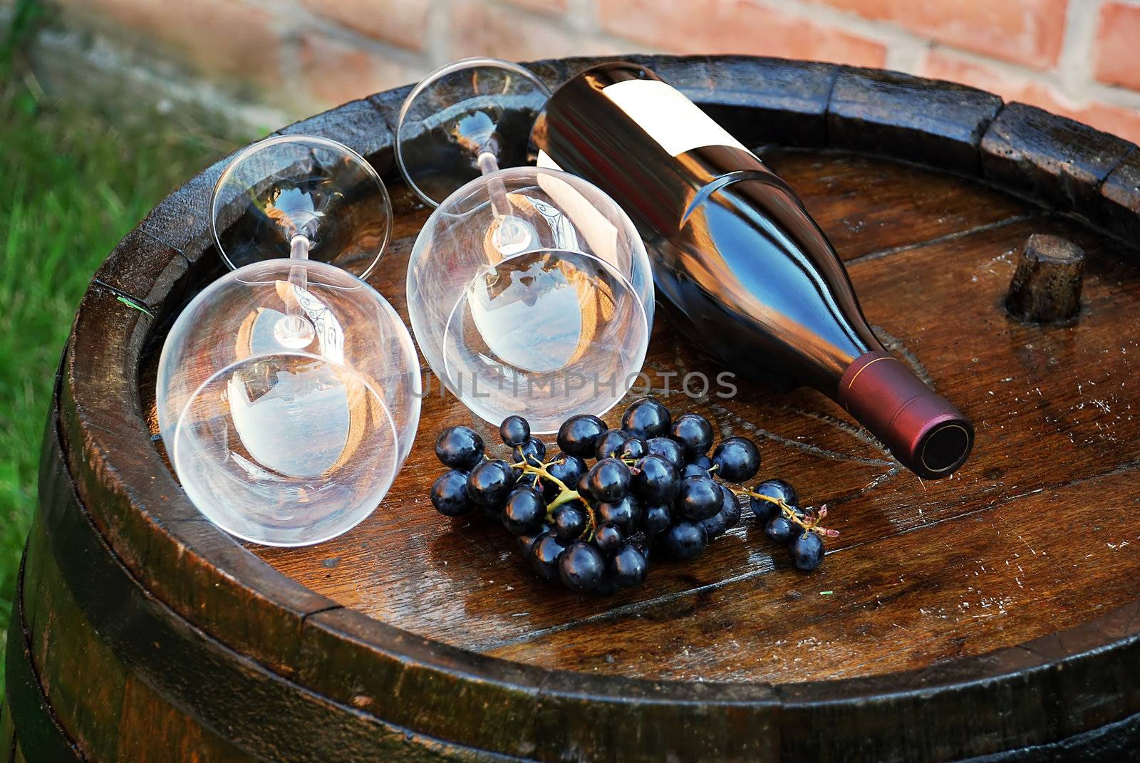 glasses and bottle of wine lying over wooden barrel