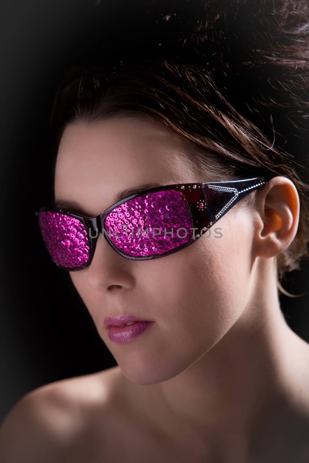 Beautiful brunette with funky sunglasses on black background