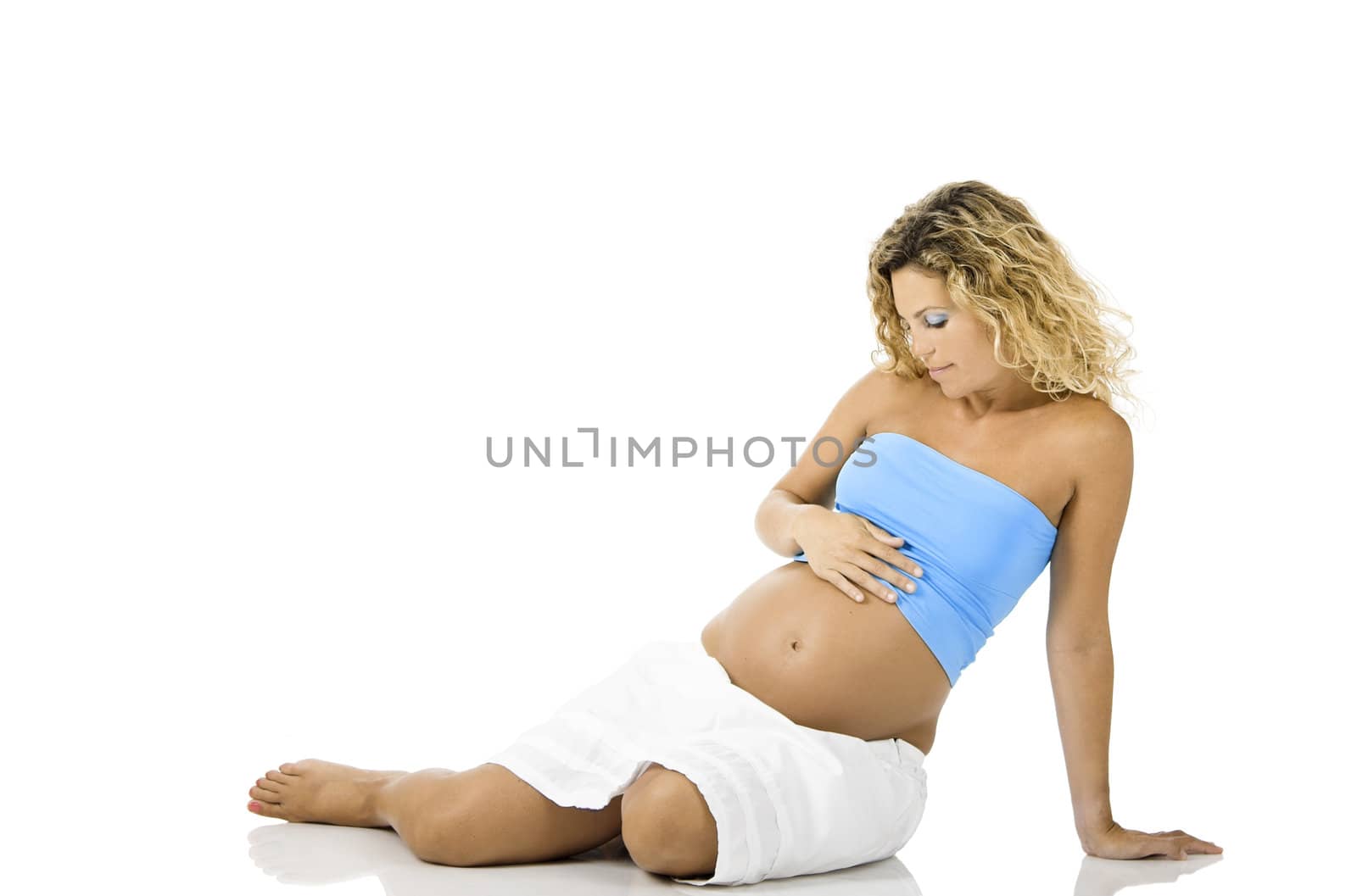 Beautiful pregnant woman seated on the floor and isolated on white background 
