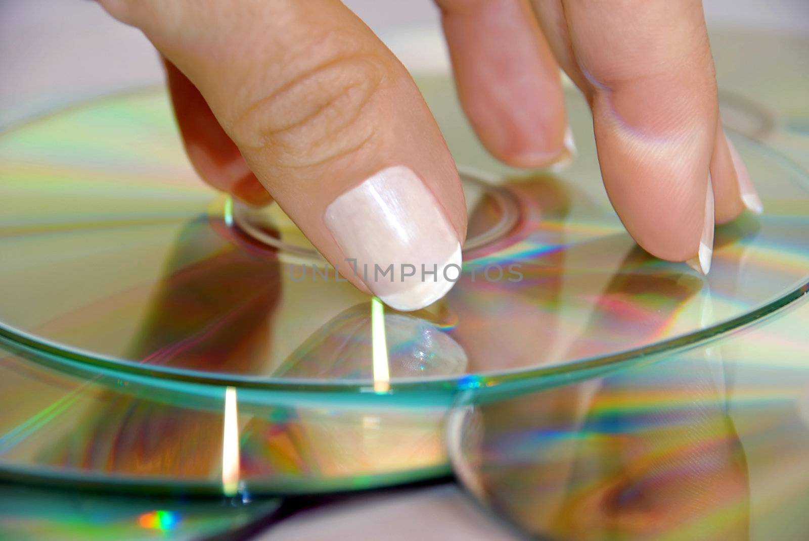 fingers with manicured nails over heap of CD