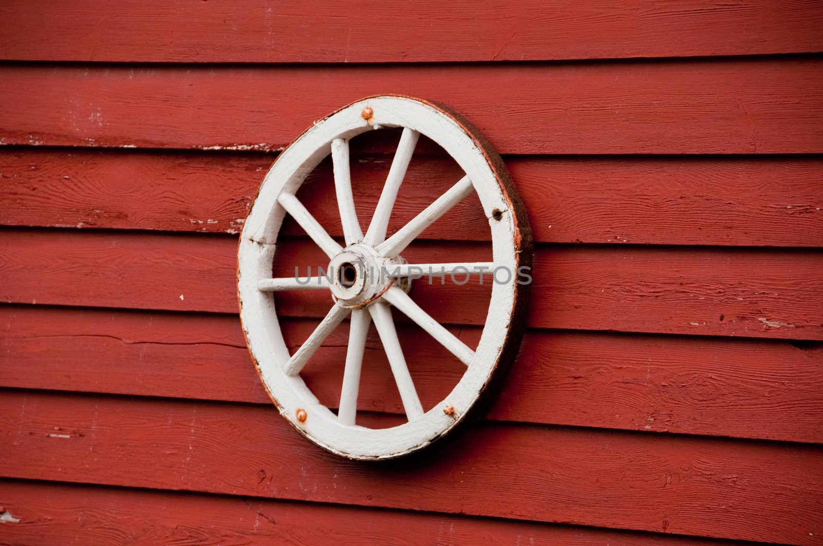 A white wagon wheel on a red wall