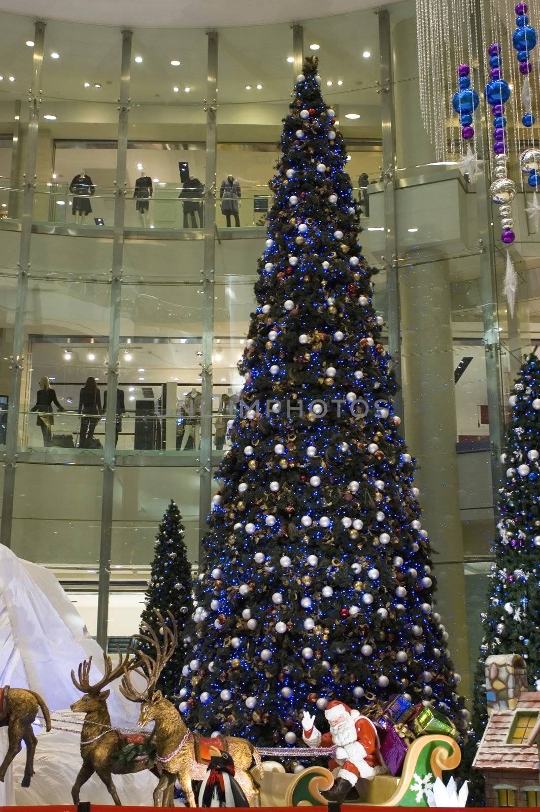 Christmas' decoration in Chinese shopping center. Happy Santa Clause, sledge and big Christmas tree.