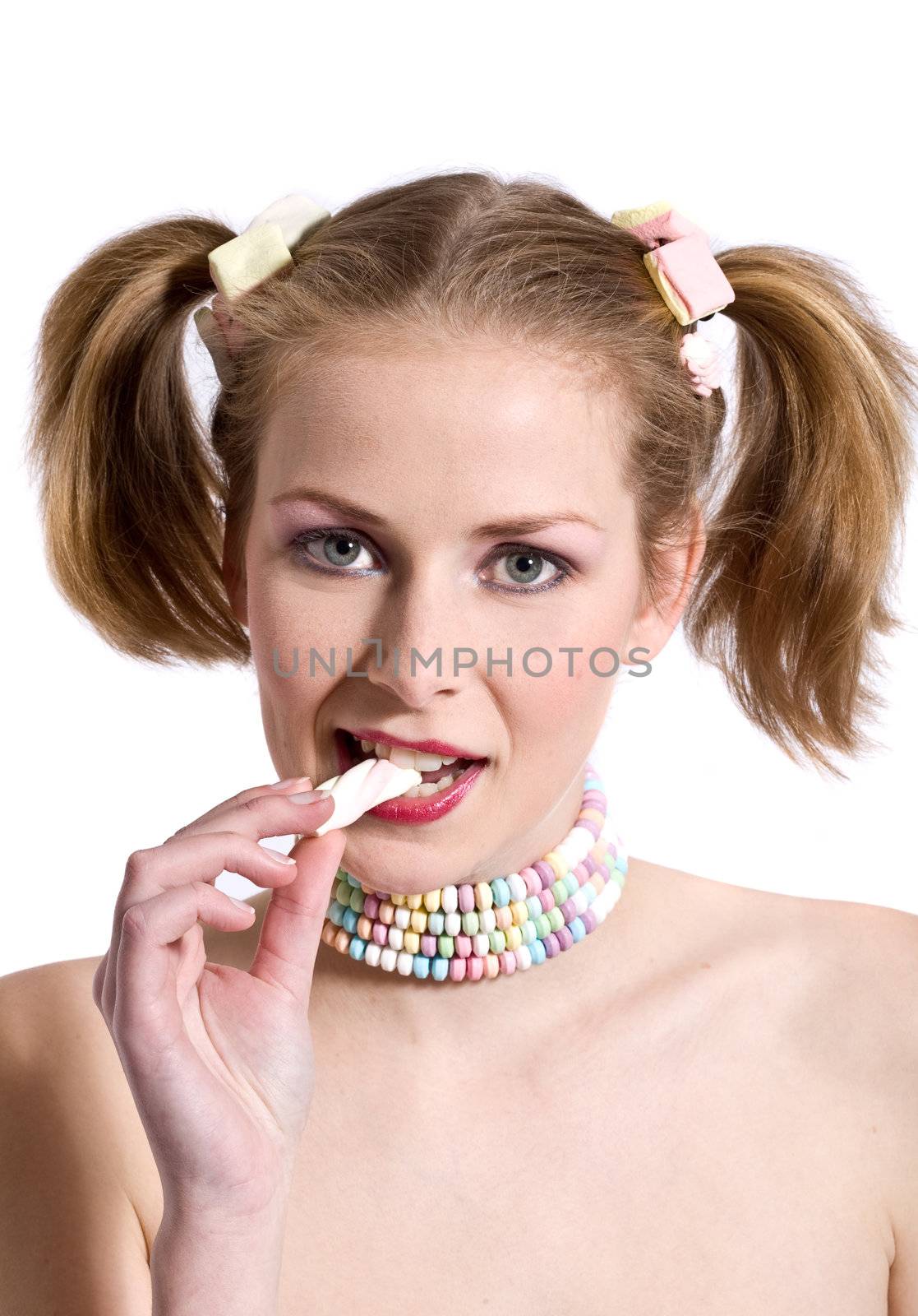Pretty blond girl with candy necklace biting in a candy