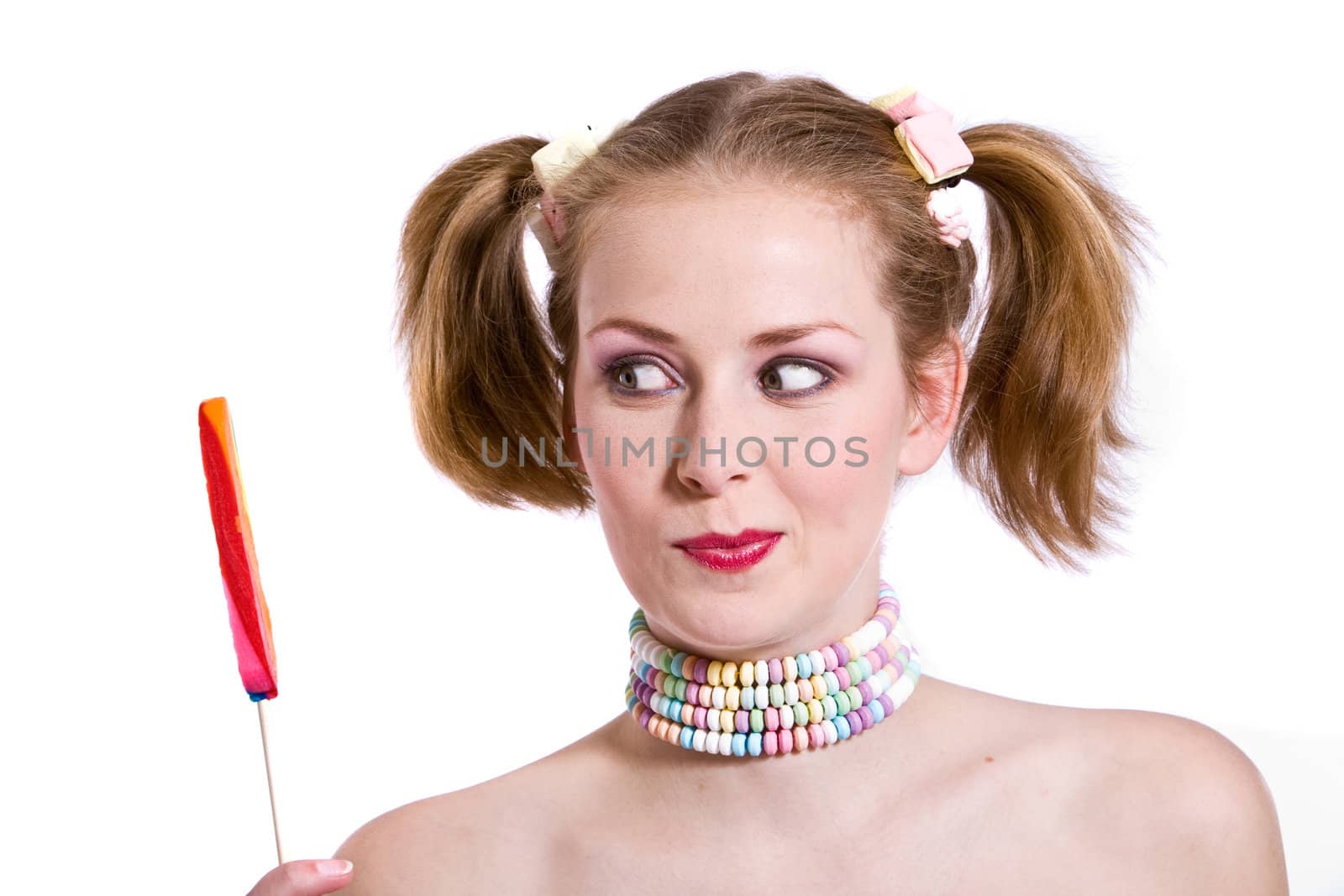 Cute young girl with two ponytails looking at a candy stick