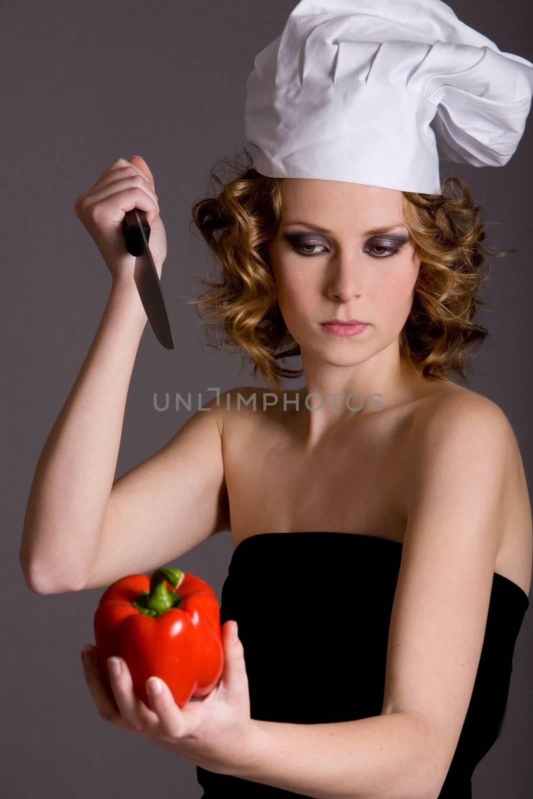 Woman with chefs hat trying to stab a pepper