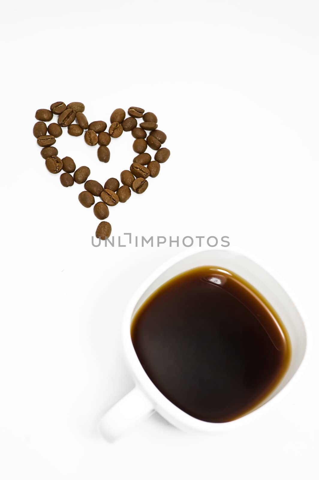 Coffee beans making heart shape and cup of coffee isolated on white