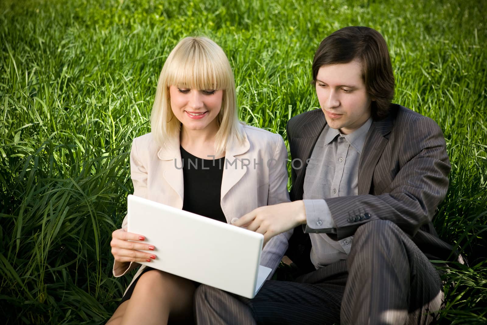 students on the grass with laptop
