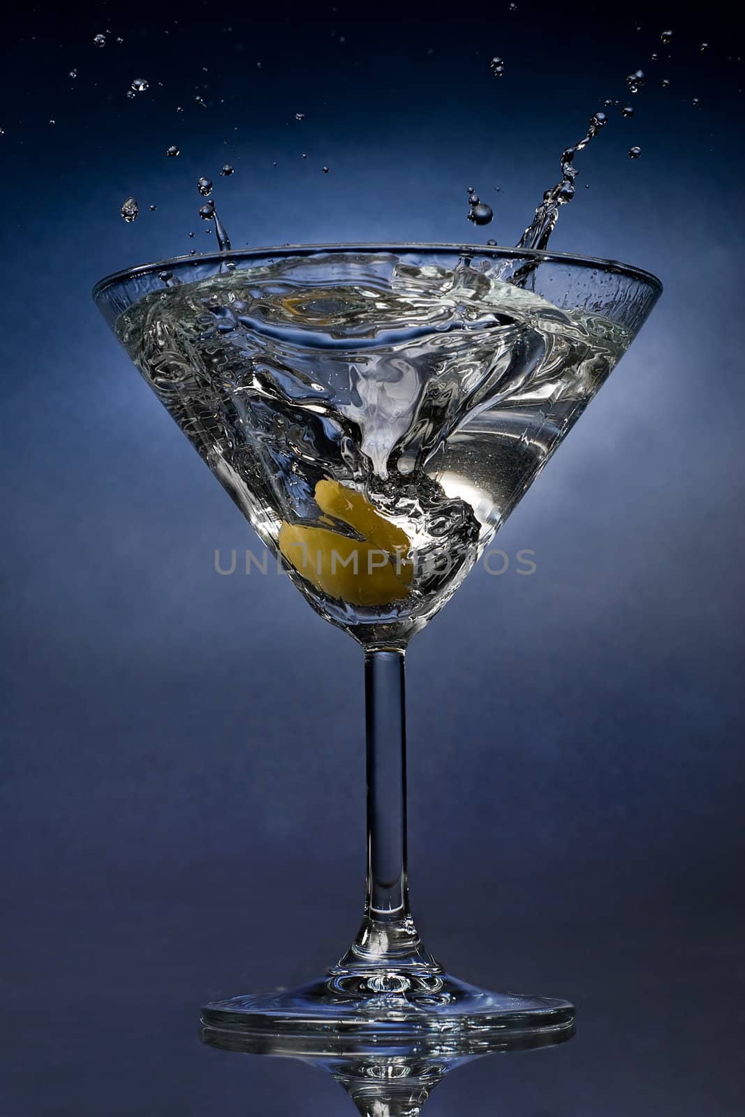 Martini cocktail splash with an olive close view