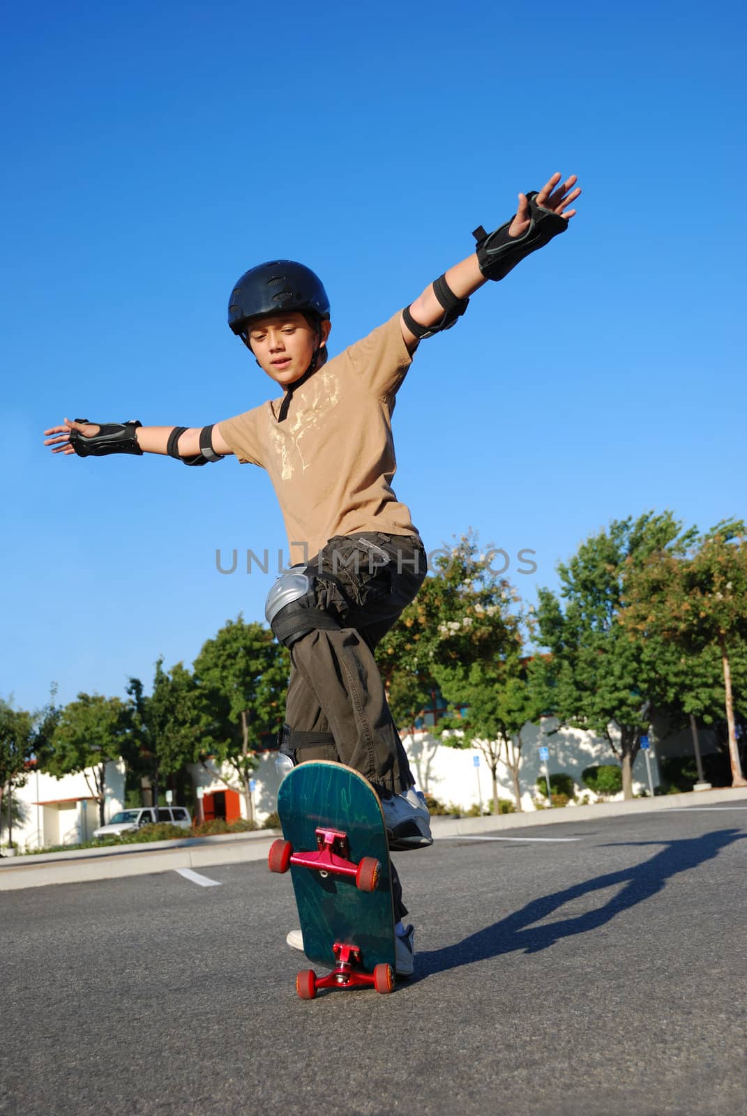 Boy doing stunts on a skateboard in afternoon sun with blue sky in the background