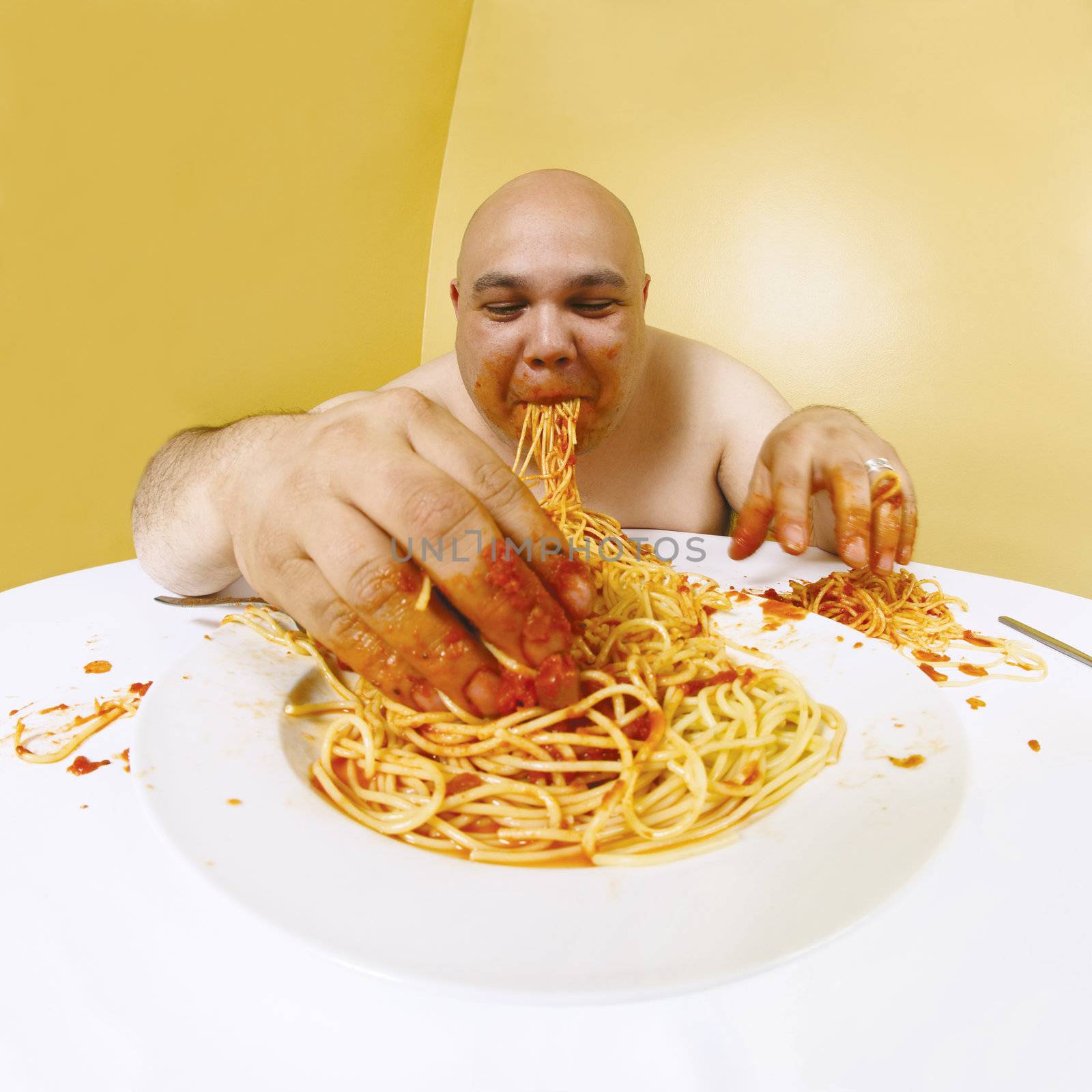 An overweight man enjoying a plate of spaghetti.  Shot with fish-eye lens.  Focus is on the face.

