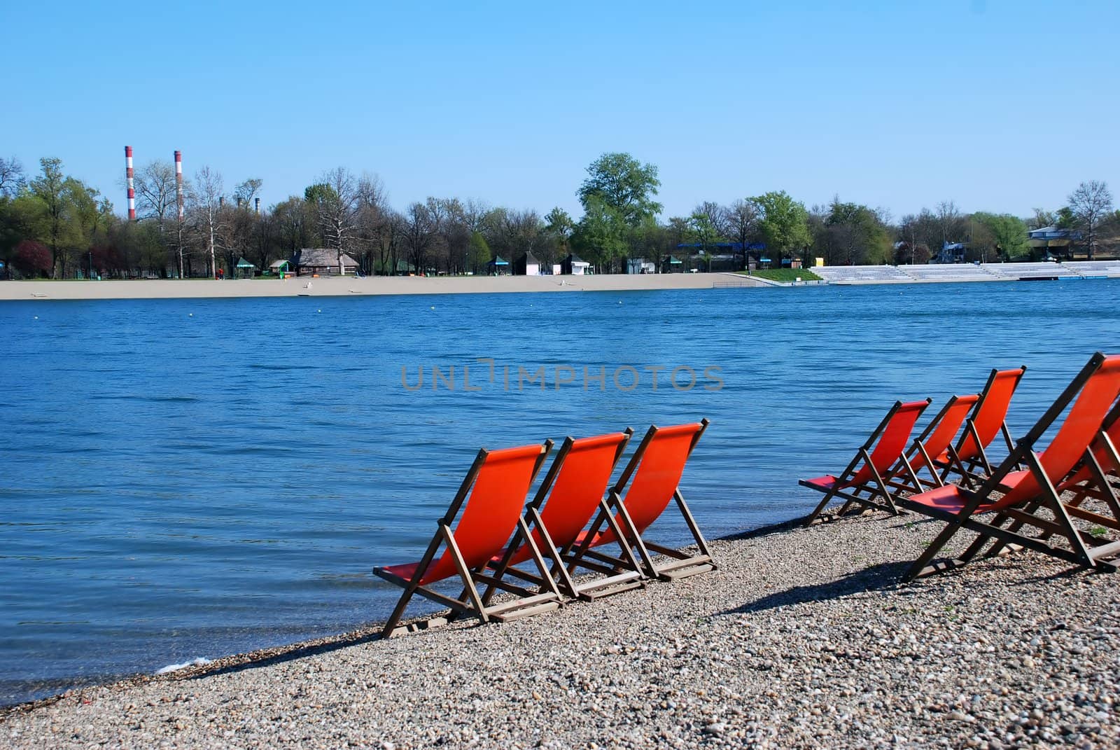three orange folding chairs by blue water