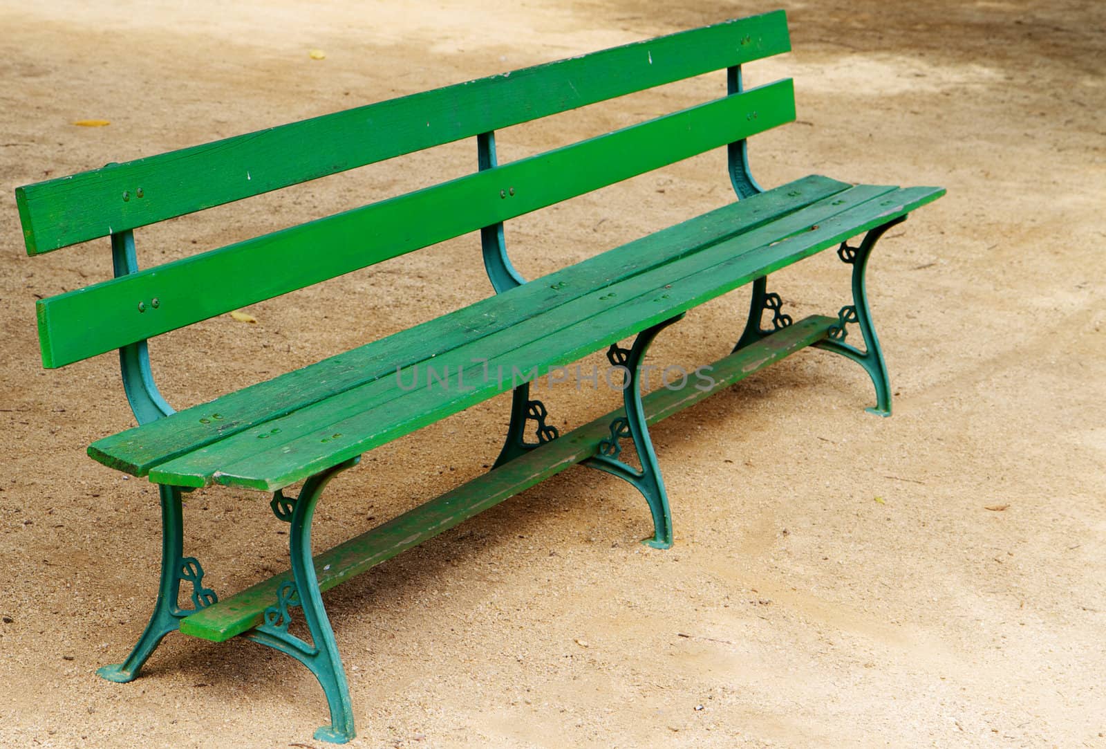 Empty green wood park bench on gravel 