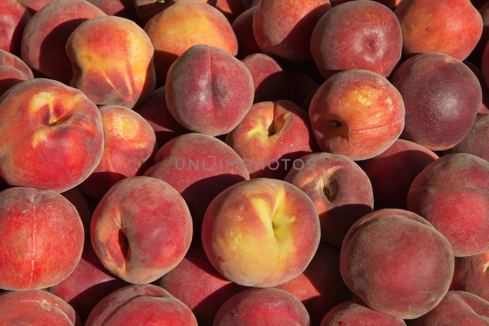 Pile of sun lit peachs at the farmers market