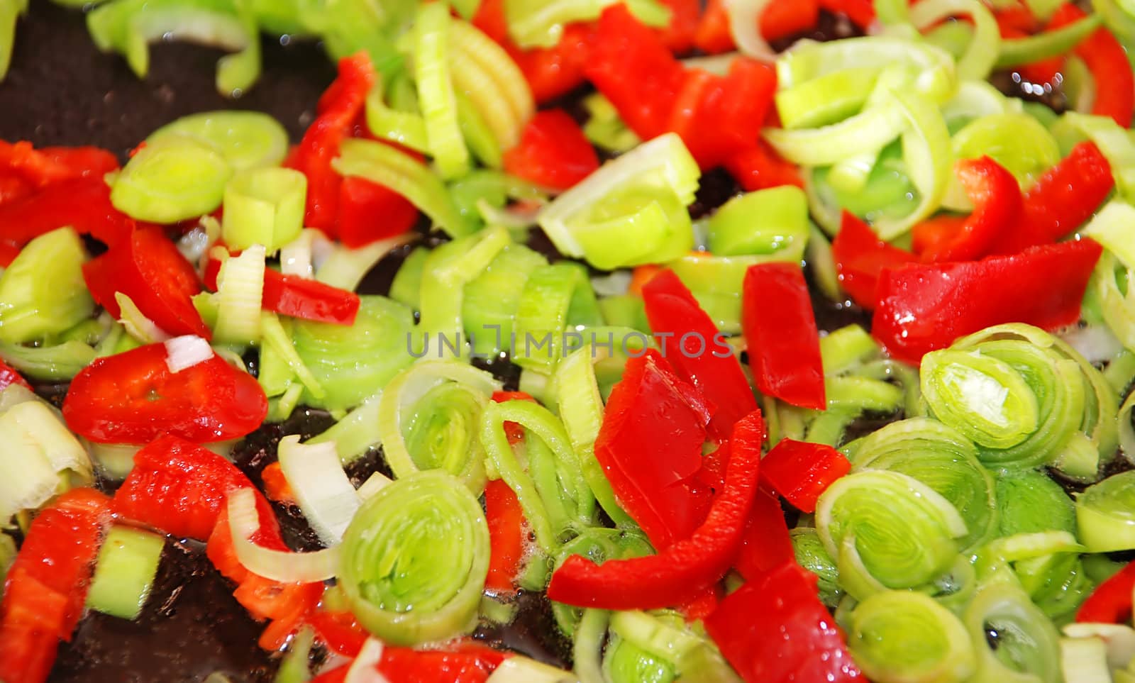 cut red paprika and green leek on frying pan